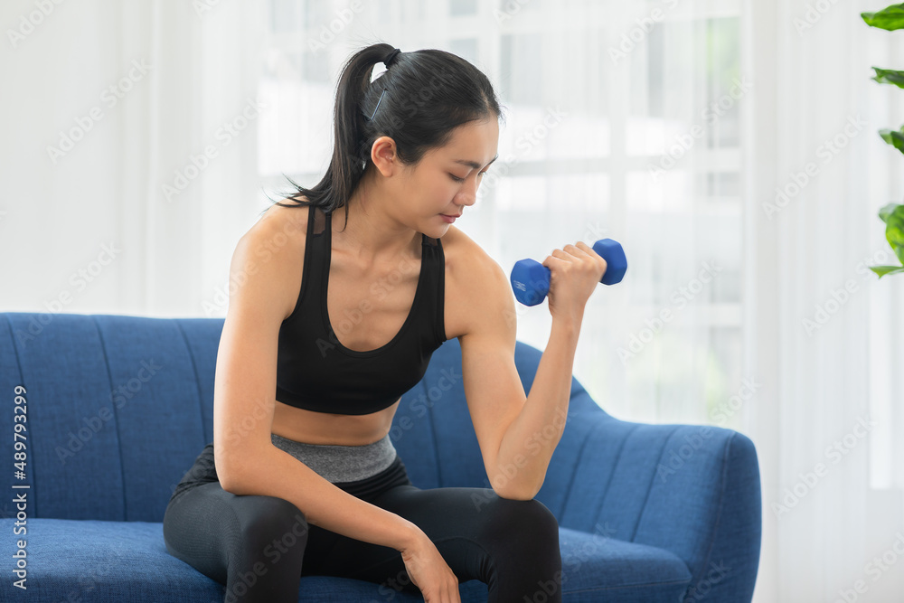 Asian young woman workout exercise with dumbbells to build bicep curl muscle.Arm day workout.Athlete woman concentration exercise on arm to focus on bicep curl.Workout and Excercise with dumbbells. Asian young woman workout exercise with dumbbells to build bicep curl muscle.Arm day workout.Athlete woman concentration exercise on arm to focus on bicep curl.Workout and Excercise with dumbbells.