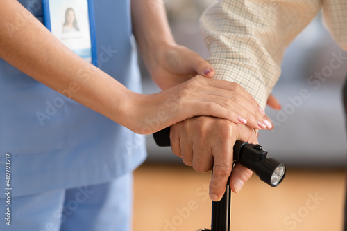 close up hand of doctor or nurse holding hand of elderly patient on cane or walking stick hope and encourage to fight comeback to walk again.Caregiver Supported and Encouraged Concept