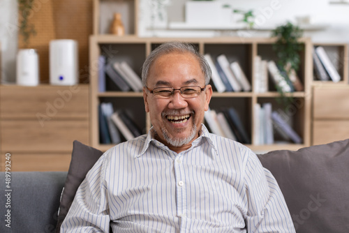 Healthy Asian Elderly man with white hairs smile and laughing so happiness and cheerful at home.Portrait of senior man sit on couch smile enjoying retirement at home .Happiness Elderly Concept