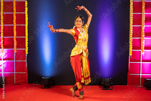 Full shot of Bharatnatyam dancer performing on stage - conept of professional artist, Indian traditional dance and culture photo
