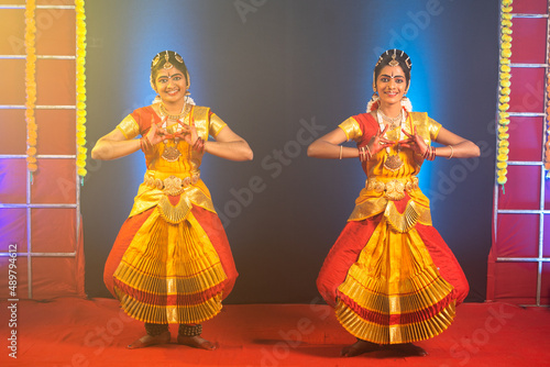 Traditional young bharathnatyam dancers performing on stage - concept of indian culture and professional classical dancers. photo