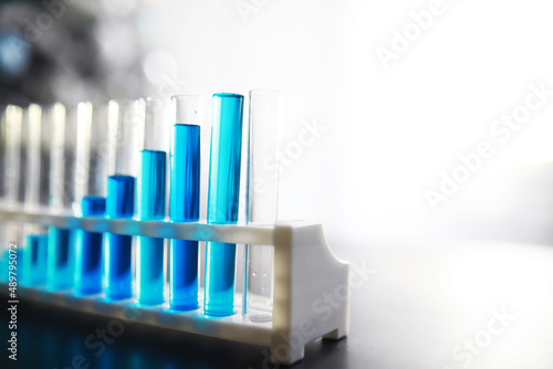 Test tube with blue liquid on the laboratory table. Examination of liquid under a microscope.