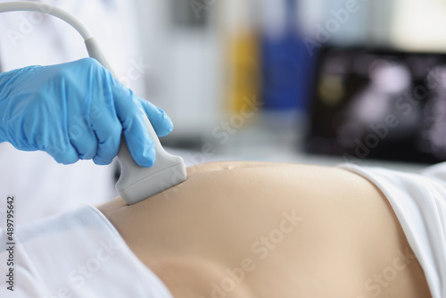 Gynecologist doing ultrasound scan on belly, doctor examining womans baby