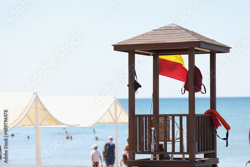 Beach with baywatch tower, no lifeguard person on post, people swimming in ocean © H_Ko