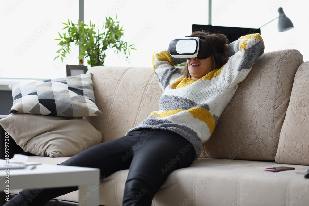 Female lay casually on couch in vr glasses, use modern device at home
