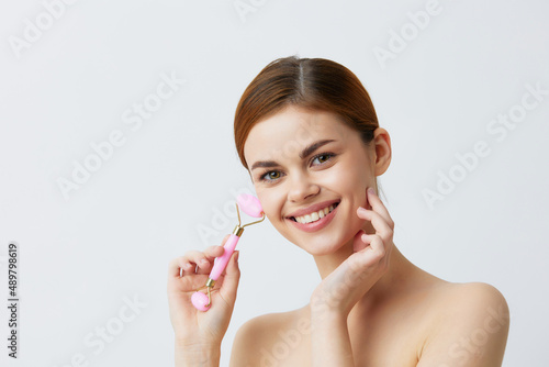 Wallpaper Mural woman massage roller anti aging facial treatment light background Torontodigital.ca