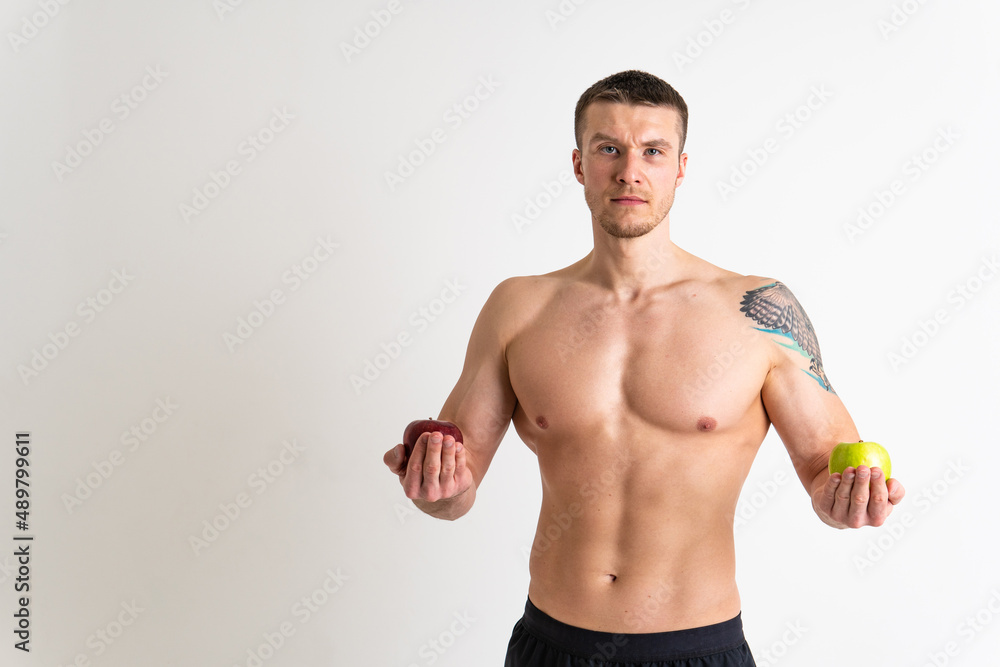 Man holds apples in fitness white background isolated man health, handsome sexy male shirtless, studio. Exercise strength red, attractive chest Man holds apples in fitness white background isolated man health, handsome sexy male shirtless, studio. Exercise strength red, attractive chest