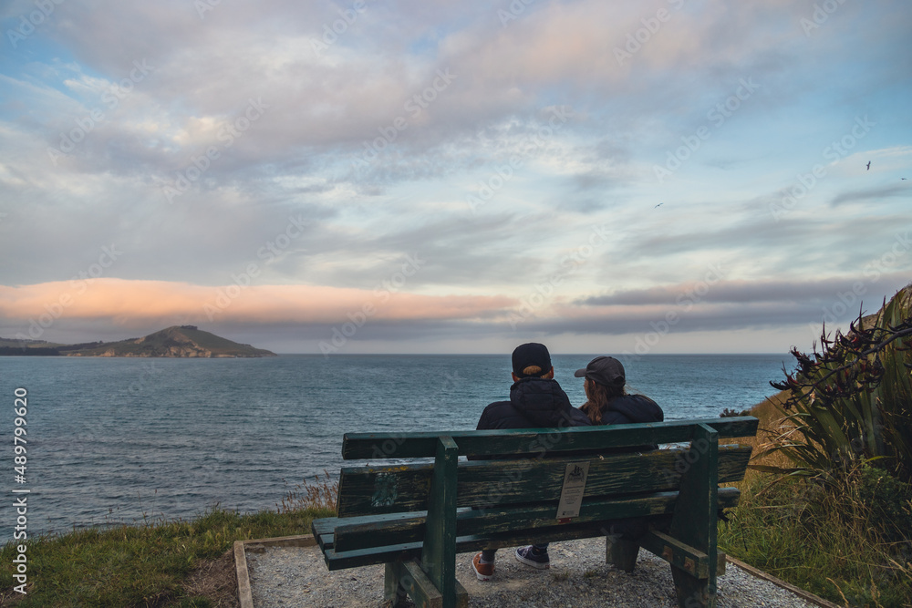 Couple sitting on bench looking at the ocean