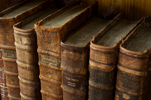 Cuadro en lienzo Dusty, worn and faded leather-bound Jewish holy books stacked upright on a library shelf