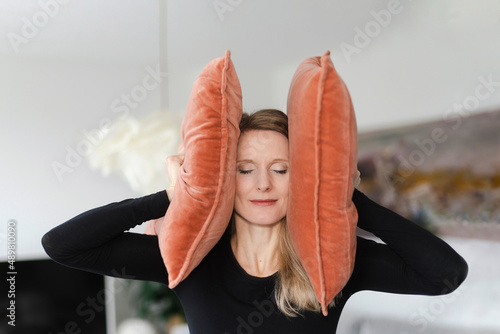 Woman covering ears with pillows at home photo