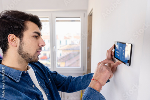 Young man using IOT home app through tablet PC at new home photo