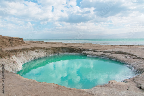 Sinkhole filled with turquoise water, near Dead Sea coastline. Hole formed when underground salt is dissolved by freshwater intrusion, due to continuing sea-level drop. . High quality photo