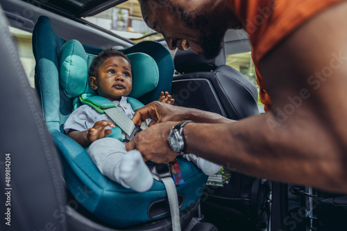 Father fastening seat belt of son in car