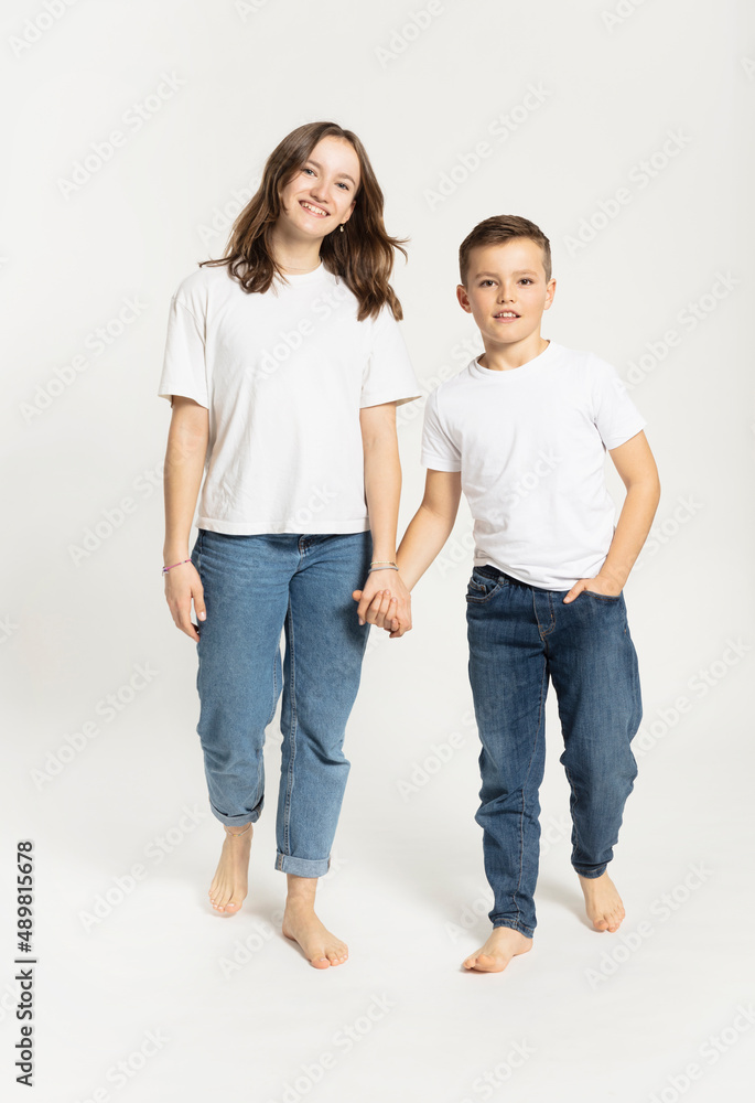 Girl holding brother's hand walking against white background Girl holding brother's hand walking against white background