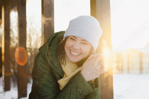 Cheerful woman sitting with hands clasped in winter