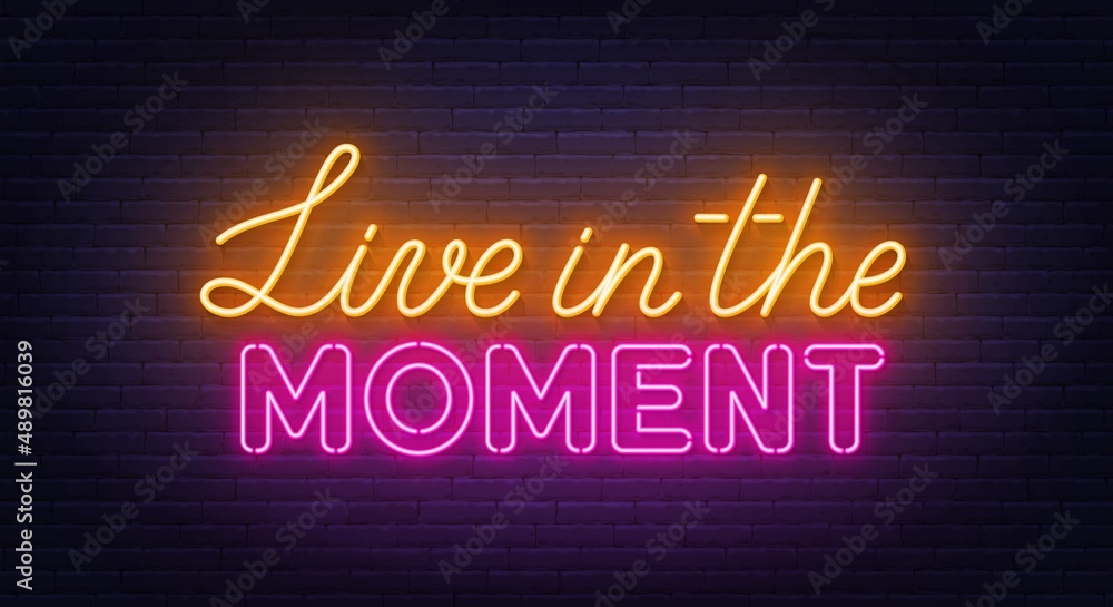 Live in the Moment neon lettering on brick wall background.
