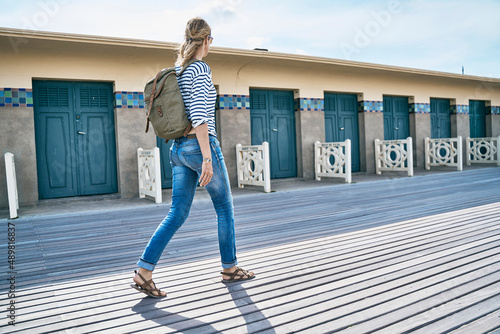Tourist walking on floorboard by beach huts photo