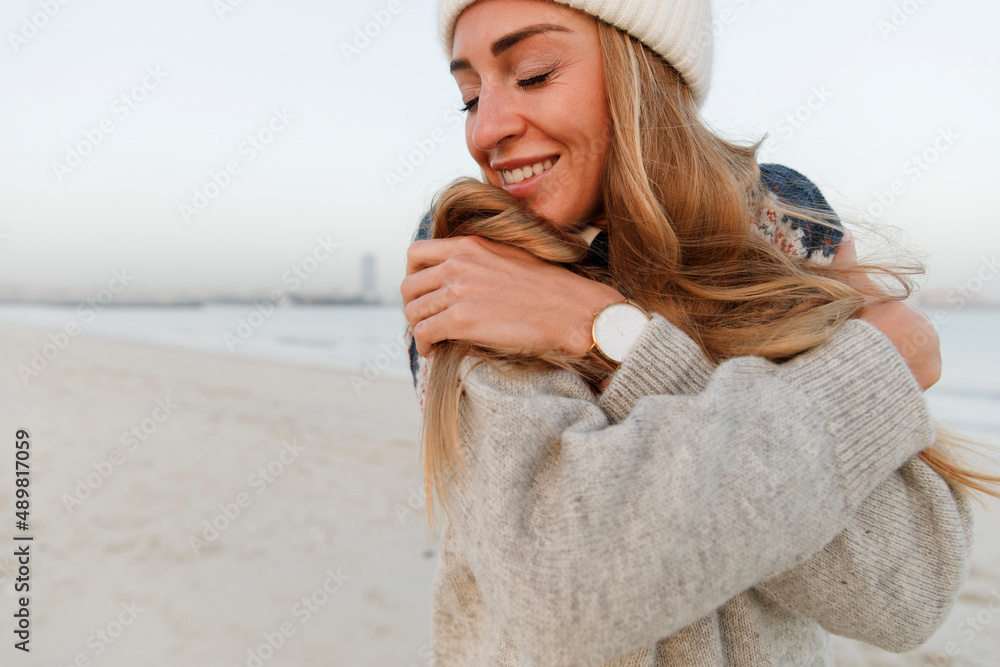 Happy woman with eyes closed hugging self at beach Happy woman with eyes closed hugging self at beach