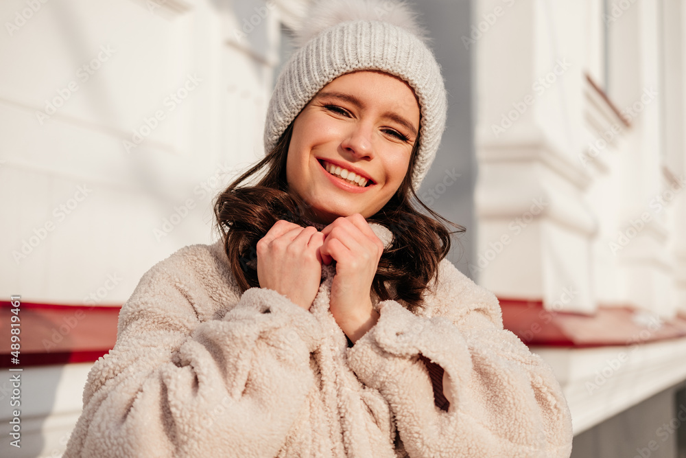 Caucasian smiling young woman in coat standing on a city street outdoors Caucasian smiling young woman in coat standing on a city street outdoors
