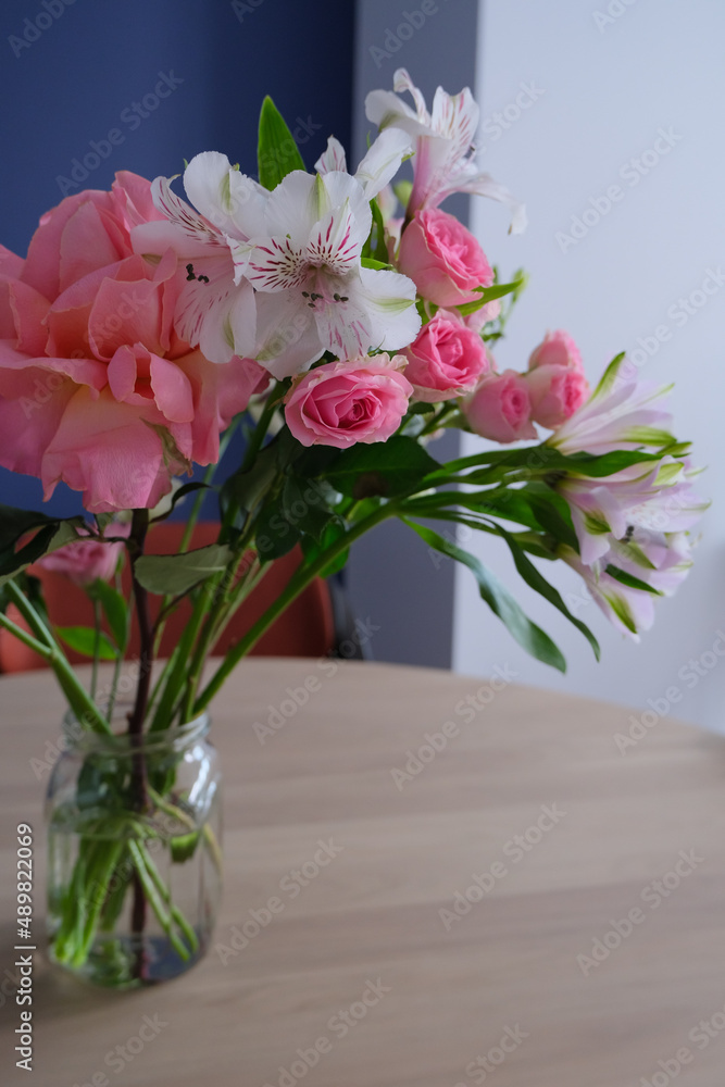 Fototapeta premium bouquet of flowers in a glass jar on wooden table in modern interior