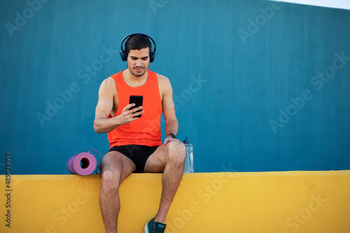 Young sexy man training outside. Fit handsome man listening the music