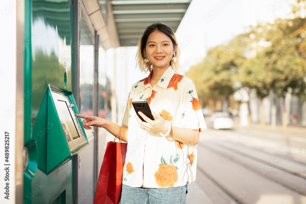 Happy smiling young woman withdrawing money from credit card. Young woman typing pin code on keypad of ATM mashine. Happy smiling young woman withdrawing money from credit card. Young woman typing pin code on keypad of ATM mashine.