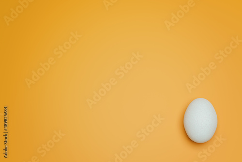 One white chicken eggs on yellow background top view. Creative food minimalistic background.