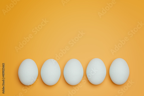 Five white chicken eggs on yellow background top view. Creative food minimalistic background.