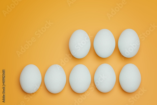 Eight white chicken eggs on yellow background top view. Creative food minimalistic background.
