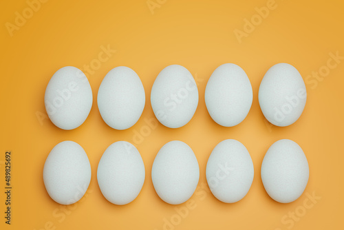 Ten white chicken eggs on yellow background top view. Creative food minimalistic background.