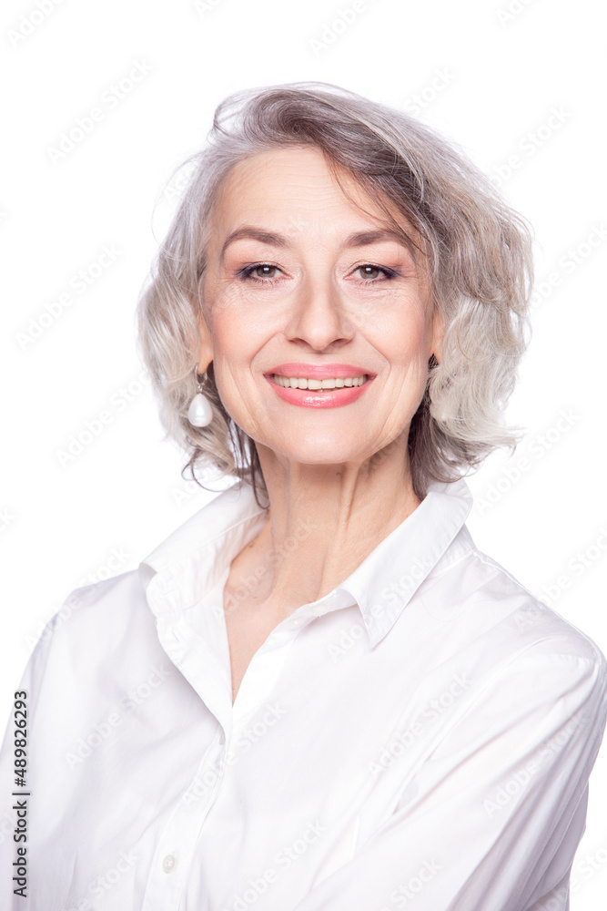Close up portrait of pleasant grey-haired middle aged female looking at camera with a wide smile and showing happiness, isolated on white studio background Close up portrait of pleasant grey-haired middle aged female looking at camera with a wide smile and showing happiness, isolated on white studio background