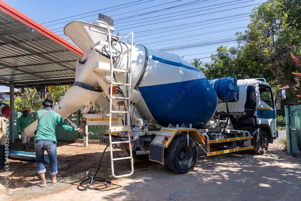 Naklejka premium Workers pouring concrete with a cement mixer truck.