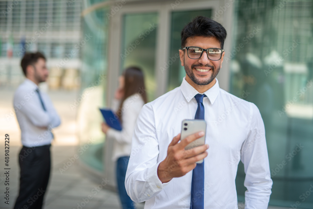 Businessman using his cellphone in front of a group of colleagues, teamwork concept Businessman using his cellphone in front of a group of colleagues, teamwork concept