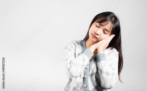 Sleep woman pretended emotions sleeping tired eyes closed dreaming with hands together near face, Portrait Asian beautiful young female sleep studio shot isolated on white background with copy space