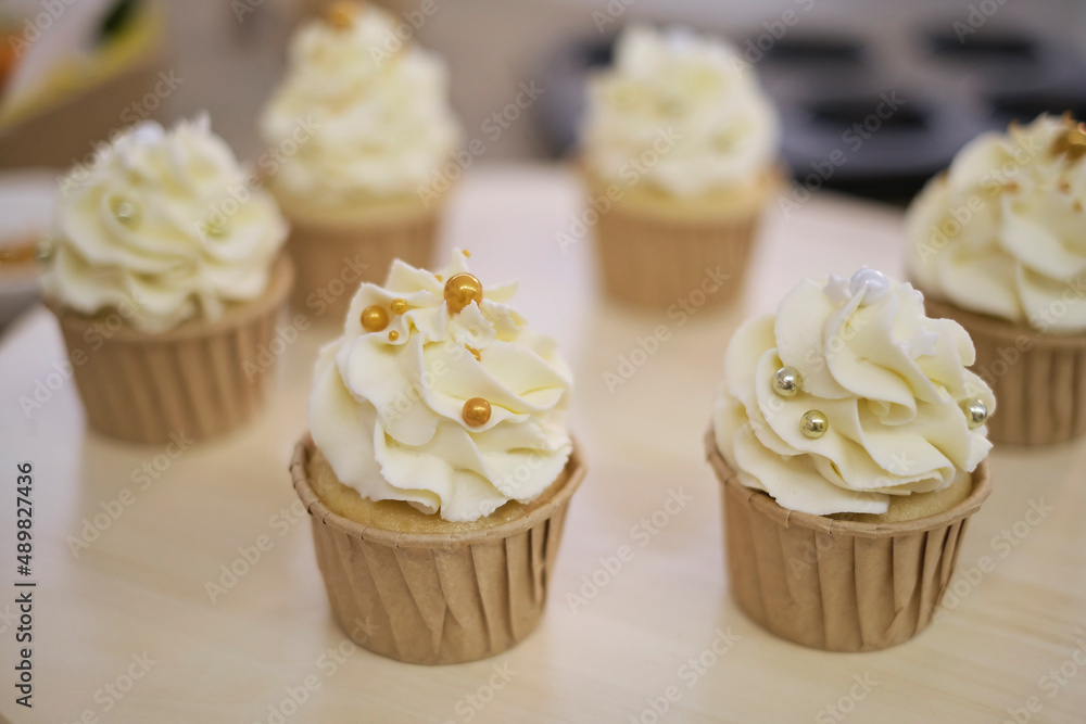 Tasty cupcakes on wooden board. Decorating a white cake with cream from the pastry bag. Tasty cupcakes on wooden board. Decorating a white cake with cream from the pastry bag.