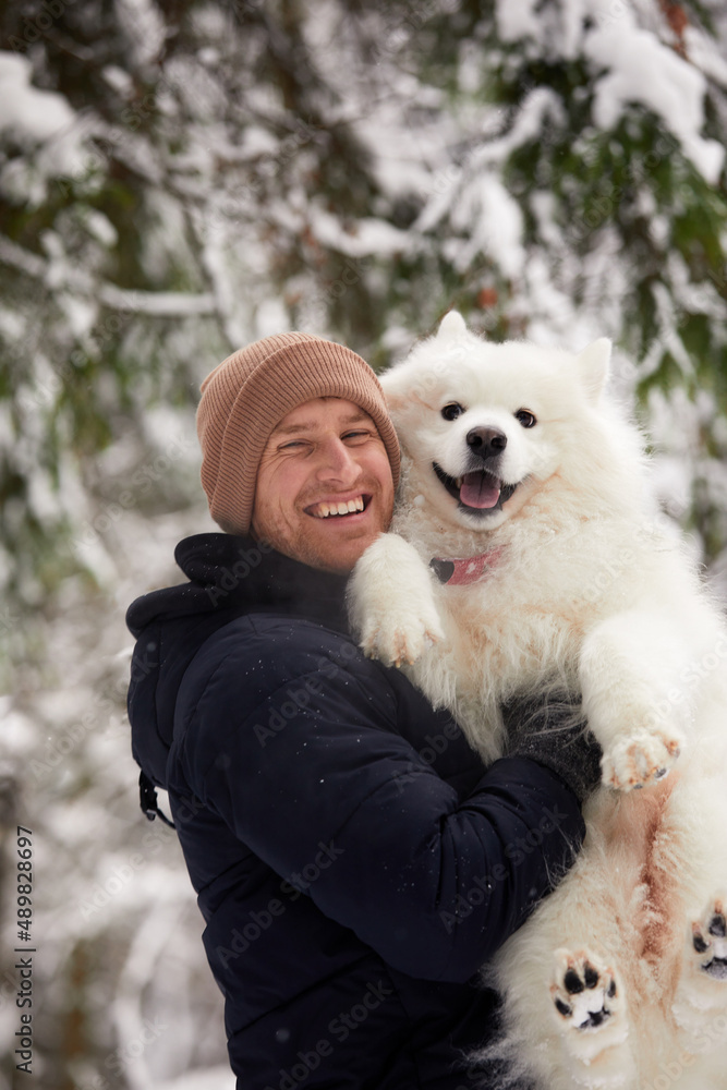 A human and a dog are best friends. Man and dog walk in snowy forest in winter in deep snow on a sunny day. A human and a dog are best friends. Man and dog walk in snowy forest in winter in deep snow on a sunny day.