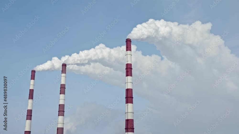 white smoke from the chimneys of a thermal power plant against the blue sky, slow motion. white smoke from the chimneys of a thermal power plant against the blue sky, slow motion.