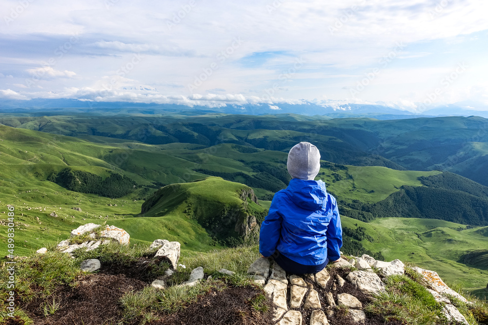 A little boy against the background of the mountains and the Bermamyt plateau in Russia. June 2021