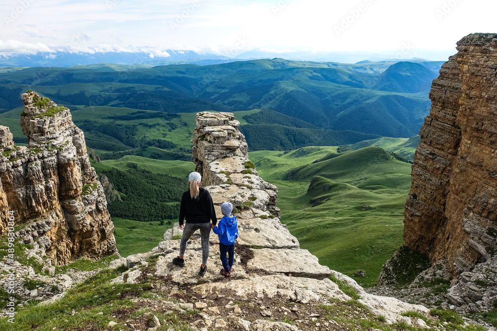 A girl with a child on the background of the mountains and the Bermamyt plateau in Russia. June 2021