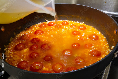 Adding stock to tomato risotto