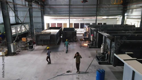 India drone fly inside manufacturing production line factory with workers welding heavy metal for trailer truck production, safety and security asian working class right photo