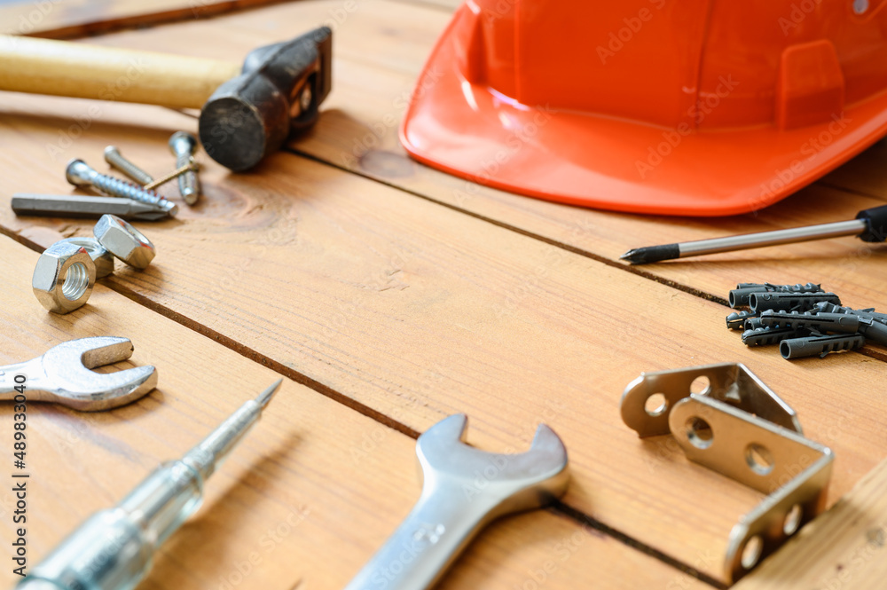 Construction tools and a construction helmet on wooden boards. Empty space in the center of the frame. Selective focus in the center of the frame.