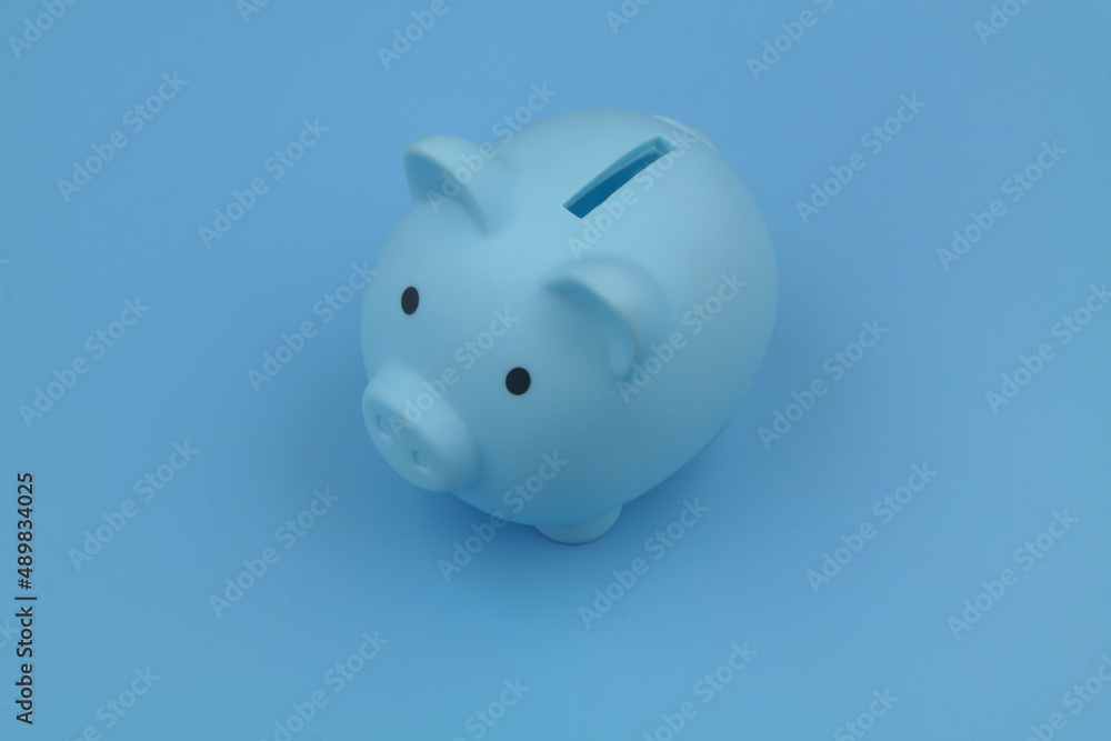 Blue piggy bank on blue background. Savings and investing concept.	