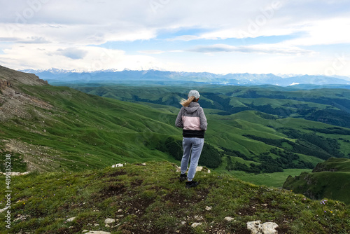 A girl on the background of the mountains and the Bermamyt plateau in Russia. June 2021