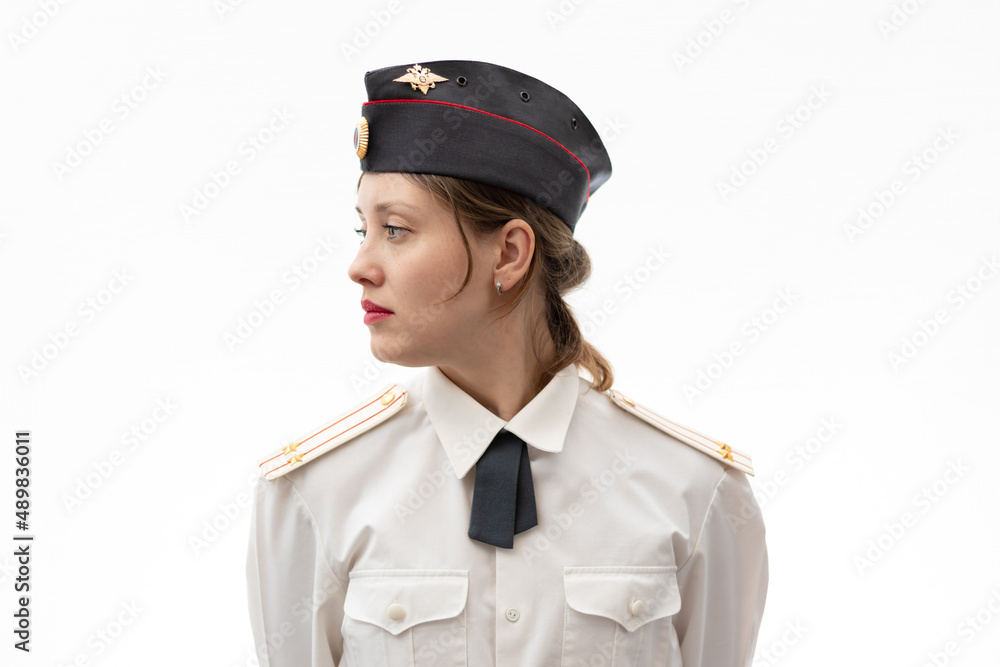A beautiful young female Russian police officer in dress uniform in a cap  and shoulder straps of a lieutenant colonel and a white shirt on a white  background. Selective focus. Portrait Stock