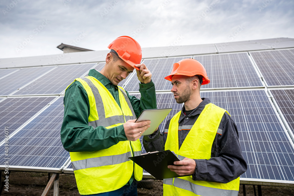 two young men in special helmets make notes after inspecting the solar panels. two young men in special helmets make notes after inspecting the solar panels.