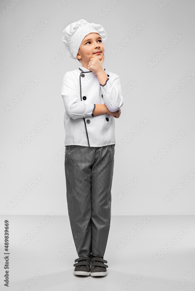 cooking, culinary and profession concept - thinking little boy in chef's toque and jacket over grey background cooking, culinary and profession concept - thinking little boy in chef's toque and jacket over grey background