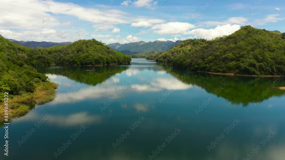 Aerial drone of river among mountains and hills with a reflecting blue sky and clouds. Randenigala reservoir, Sri Lanka. Aerial drone of river among mountains and hills with a reflecting blue sky and clouds. Randenigala reservoir, Sri Lanka.