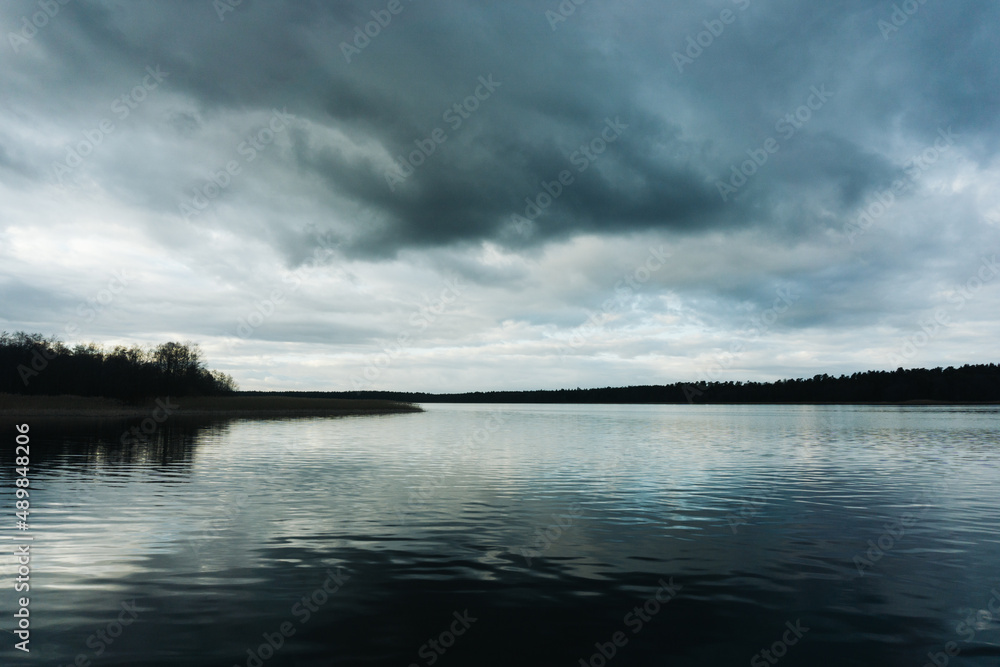 Dark lake landscape. Stormy weather scenic view. Melancholic landscape. Rainy day by the lake. Sad panoramic background.