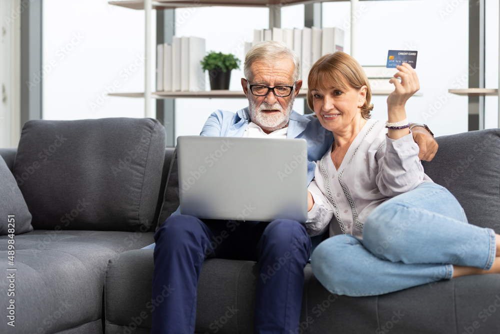 senior couple using laptop computer and credit card for shopping online on sofa senior couple using laptop computer and credit card for shopping online on sofa